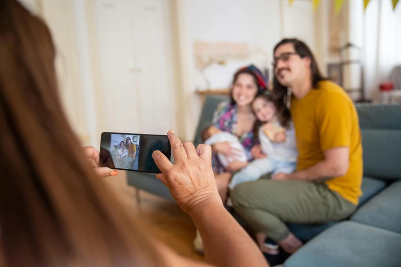 a young woman and man sitting on a couch with their baby in a room