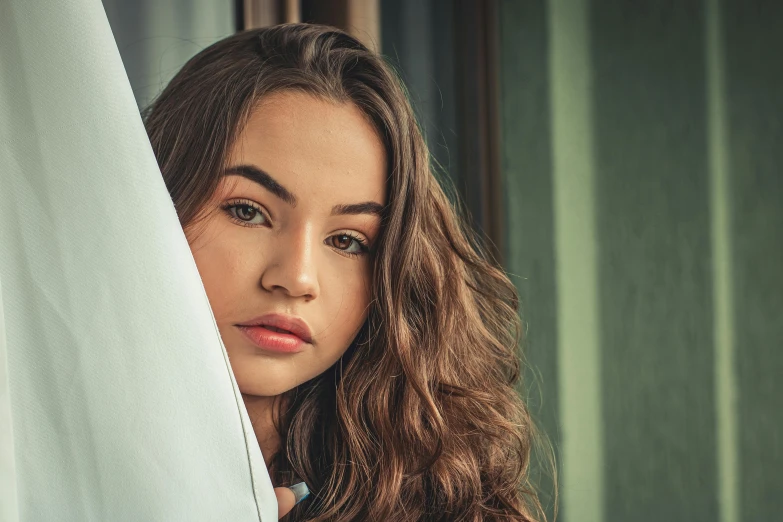 a girl with long hair is holding curtains