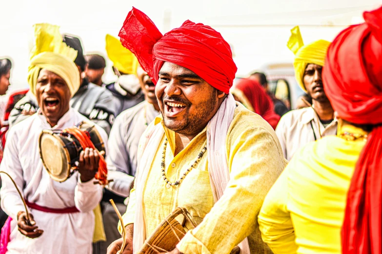 some men with red turbans are playing the drums