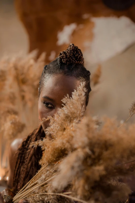 a smiling woman holding some dried flowers on her face