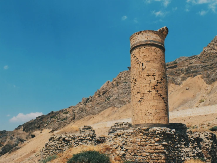 a stone tower stands in the desert by a mountain