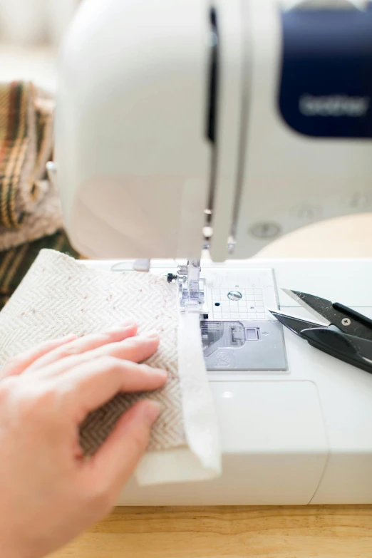 someone using a sewing machine to thread fabric
