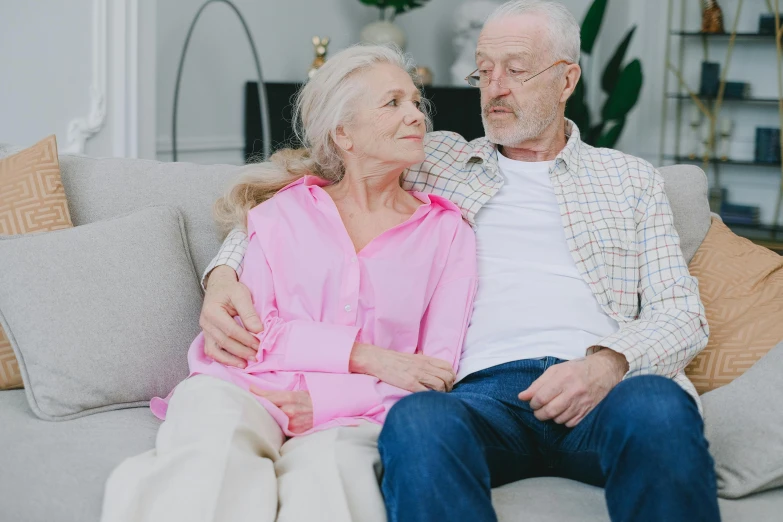 an older man and woman sitting on the couch together