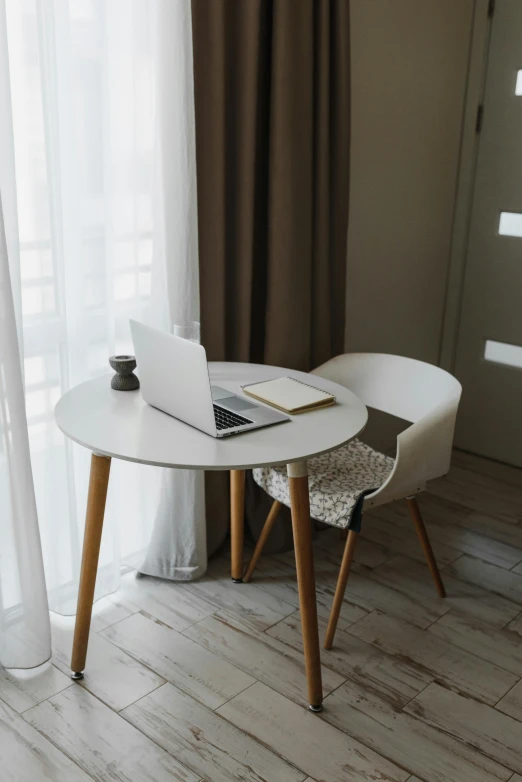 a laptop on a table next to two chairs in a room