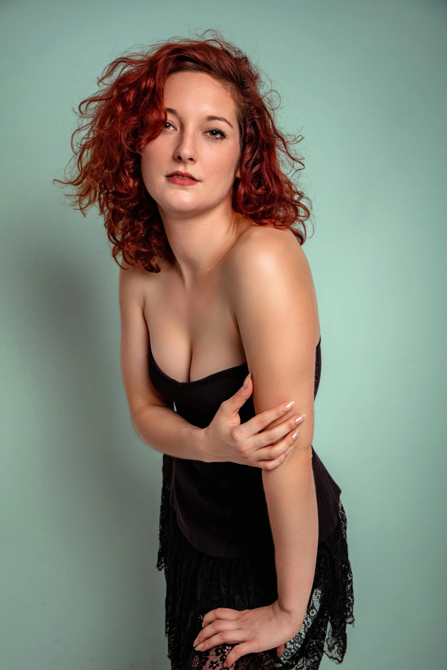 a woman with red hair is posing in an all black dress