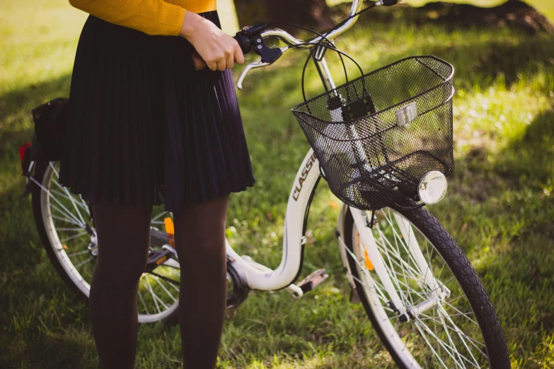 woman in a yellow sweater stands next to her bicycle