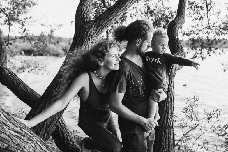 a couple standing near trees and water smiling at a woman