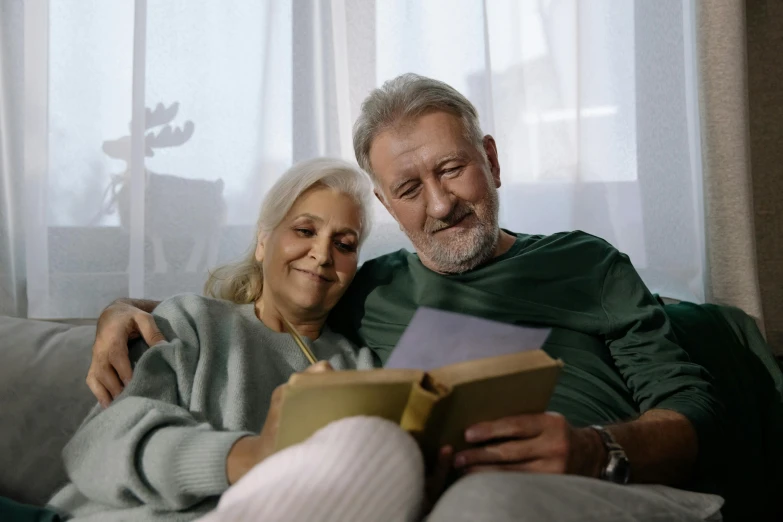 an elderly couple looks over the papers as they sit on a couch