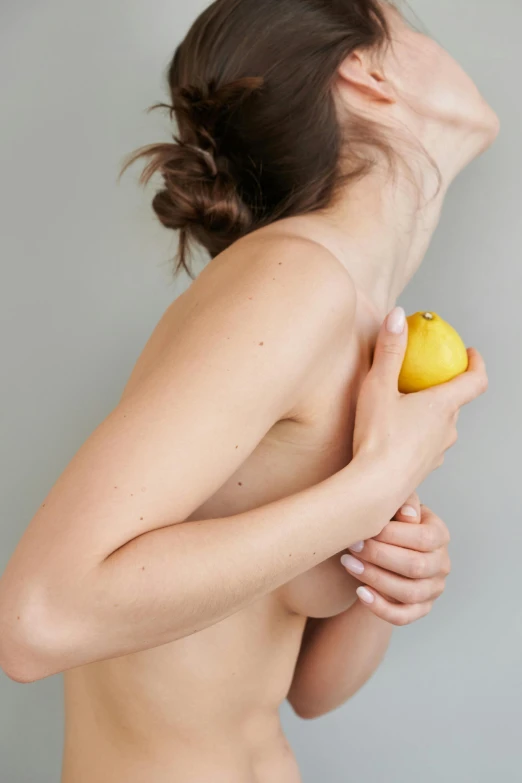 a  female holding a lemon and posing for the camera
