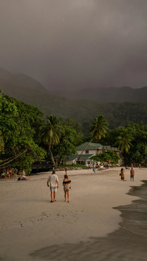 the people are walking down the beach towards the water