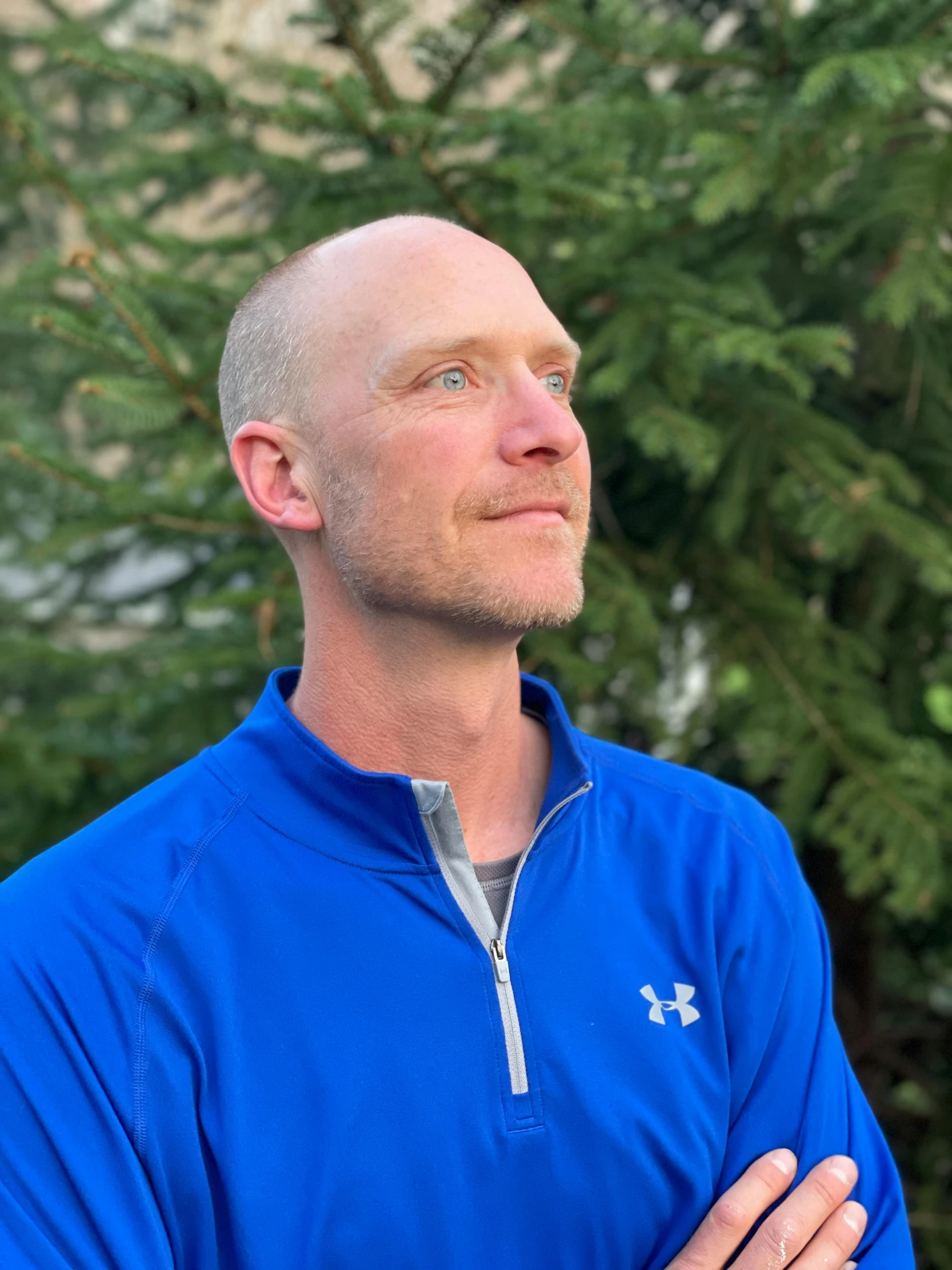 a man in a blue jacket stands in front of some trees