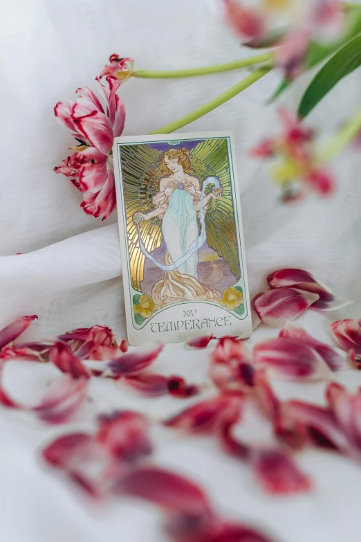 a tarot card sitting on a sheet surrounded by flowers