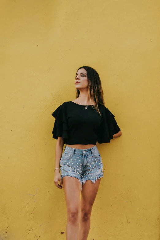 a young woman posing for the camera against a yellow wall