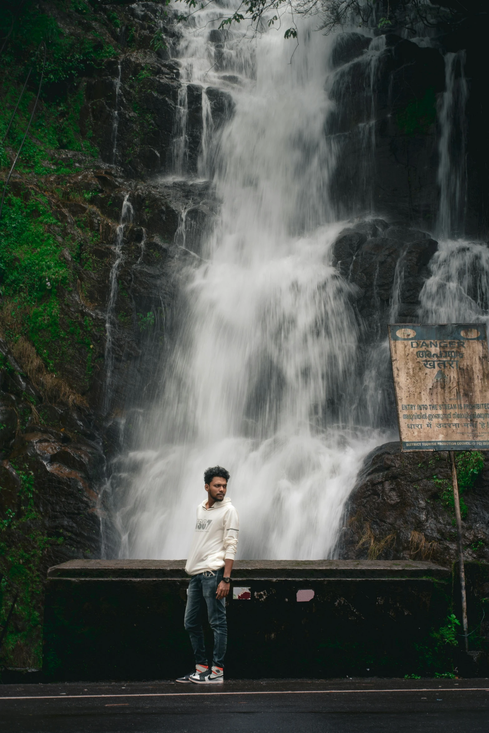 a young man is standing near a waterfall