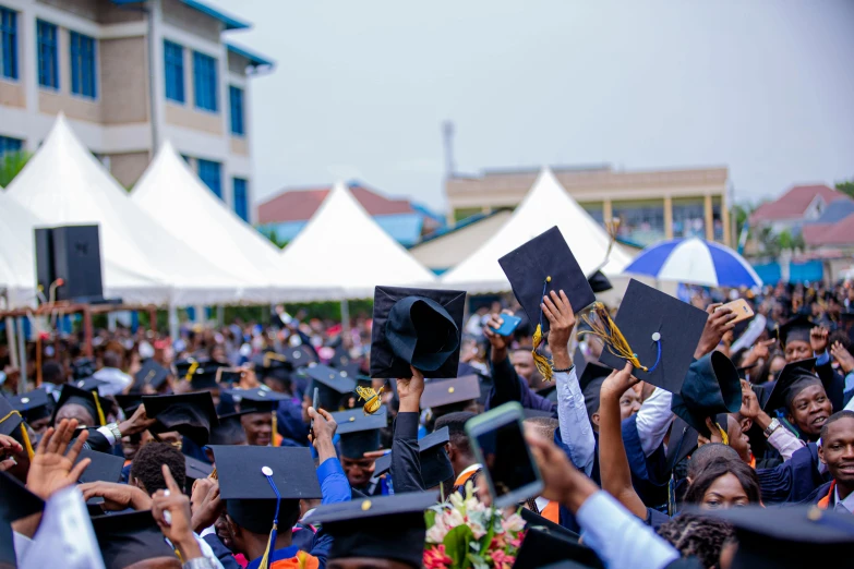 a crowd of graduates with their caps raised in a graduation ceremony