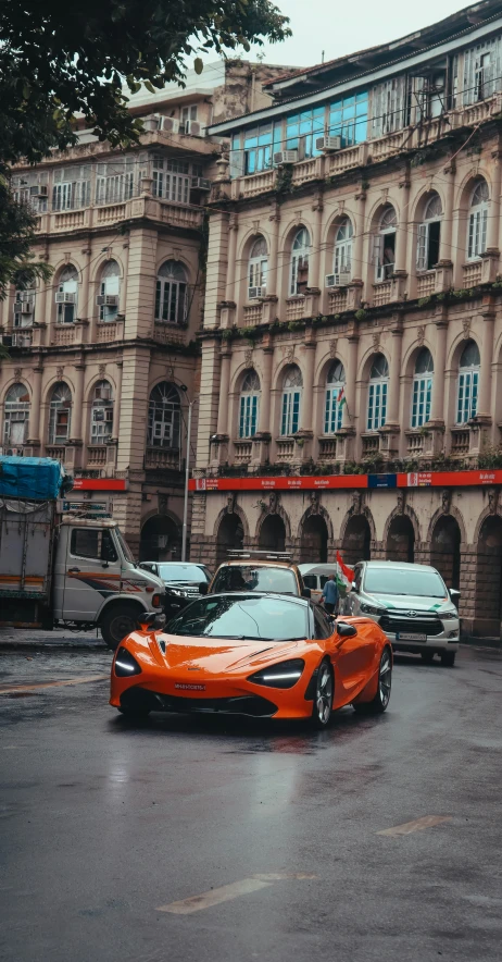 orange sports car parked in front of a building