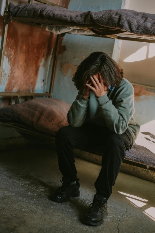 a man is sitting on a bed with his hand on his face