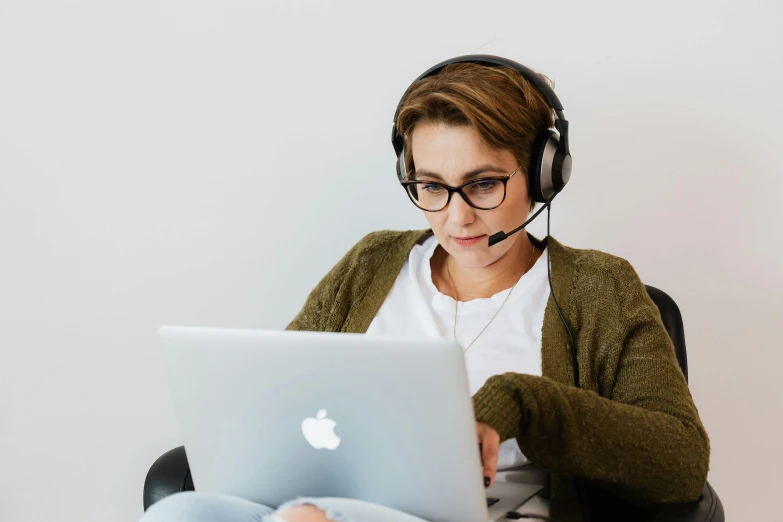 a woman wearing headphones and looking at her laptop