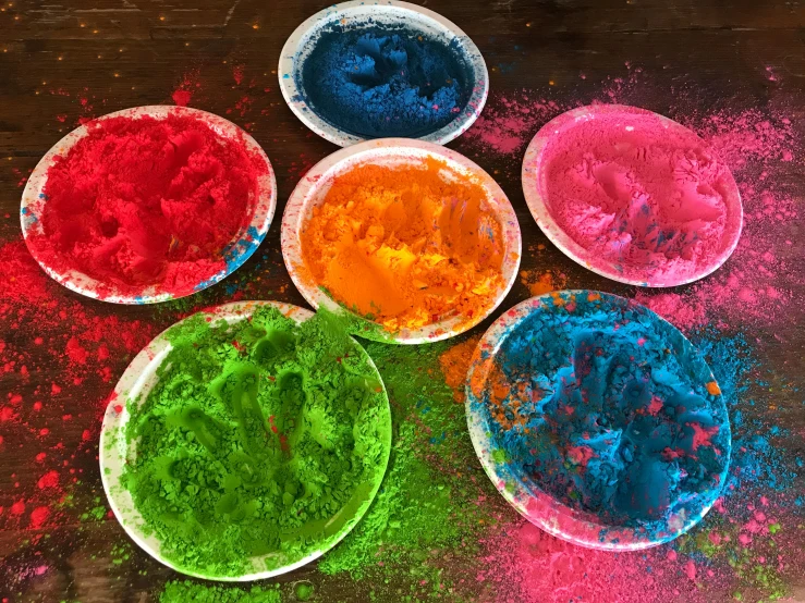 a few plates of colored powder on top of a table