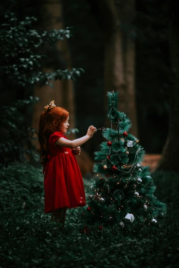 a little red headed girl is touching a small tree