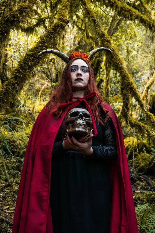 a person with horns holding a human head in a forest