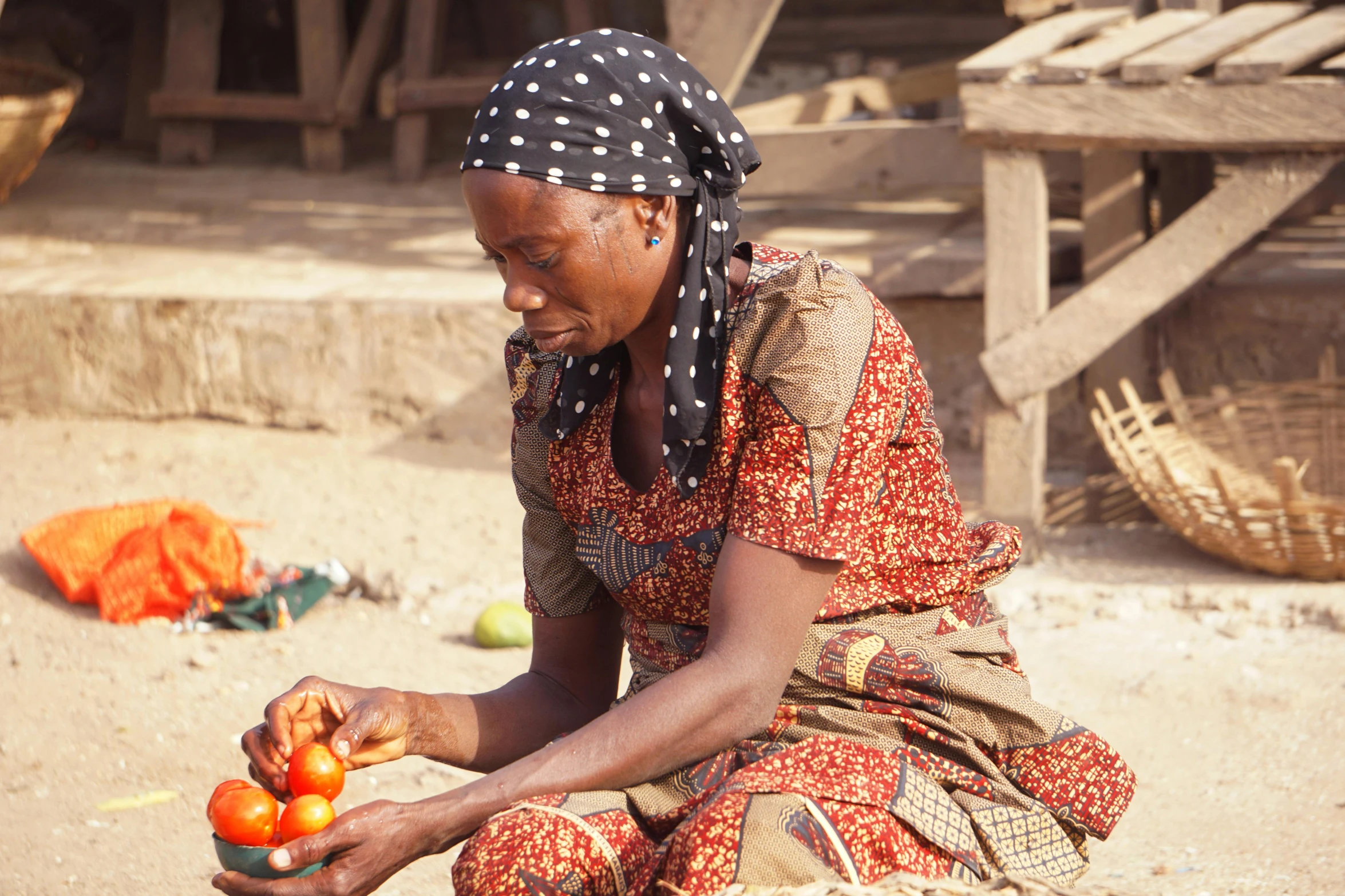 a woman wearing an orange head scarf sitting on a beach