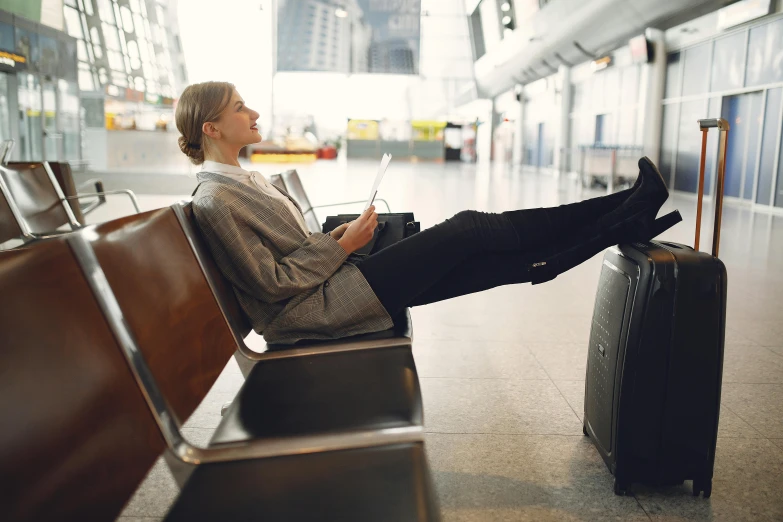 a woman sits on an airport bench next to her luggage