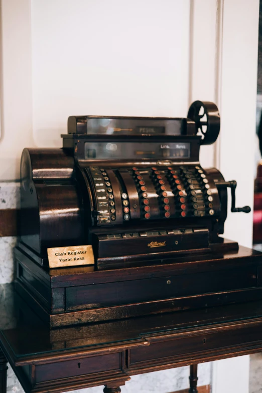 an old - fashioned metal - framed cash register sits on a wooden shelf