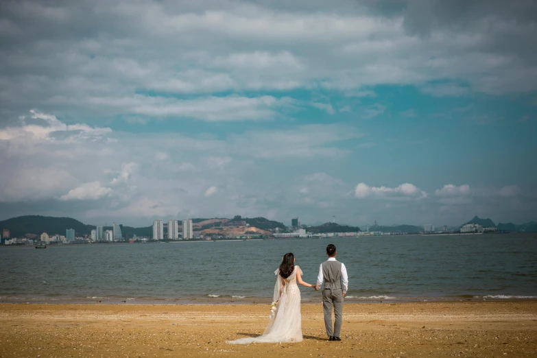 the bride and groom are on the beach next to the ocean