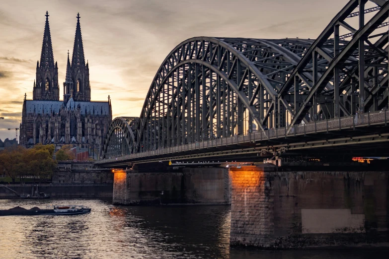 a cathedral rises above the city from a river under a bridge