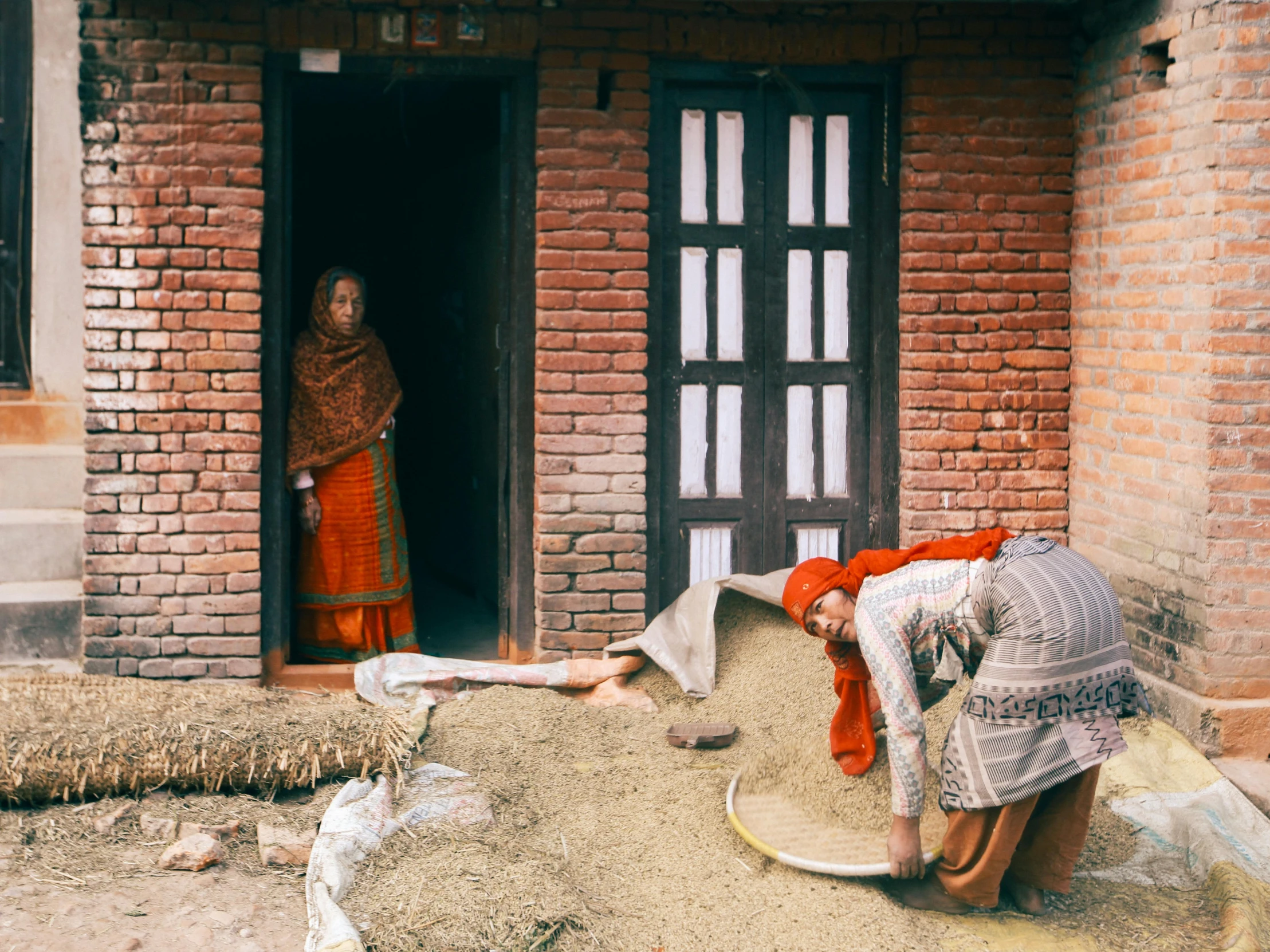 two woman standing in the doorway of a brick house