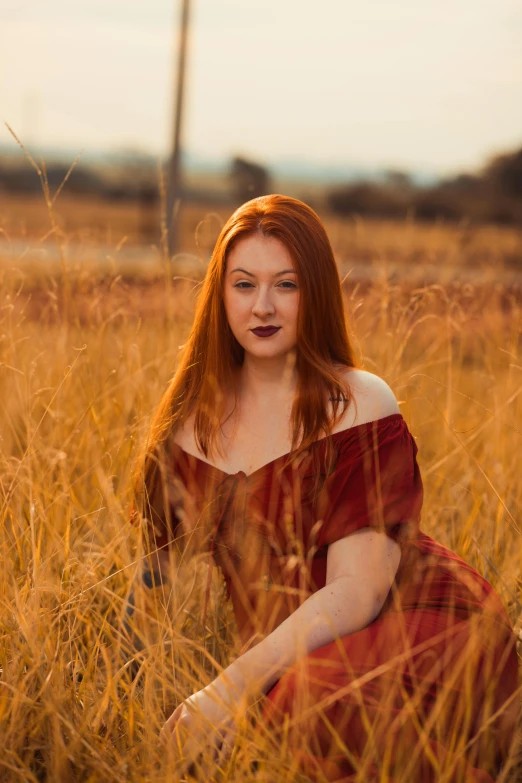 young woman with red hair sitting in an orange field