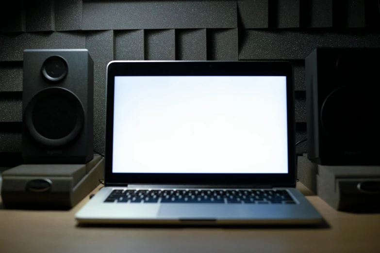 an open laptop on a desk in front of sound speakers
