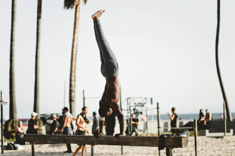 a person on a beach doing an upside - down yoga pose