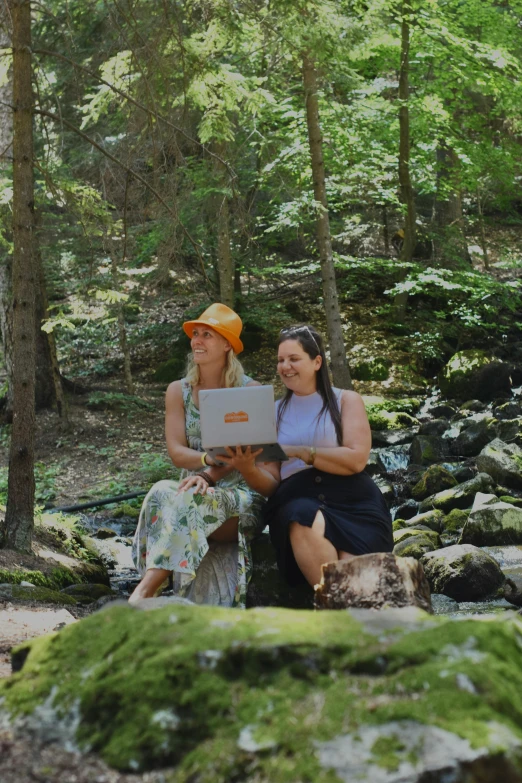 two women sitting next to each other on rocks