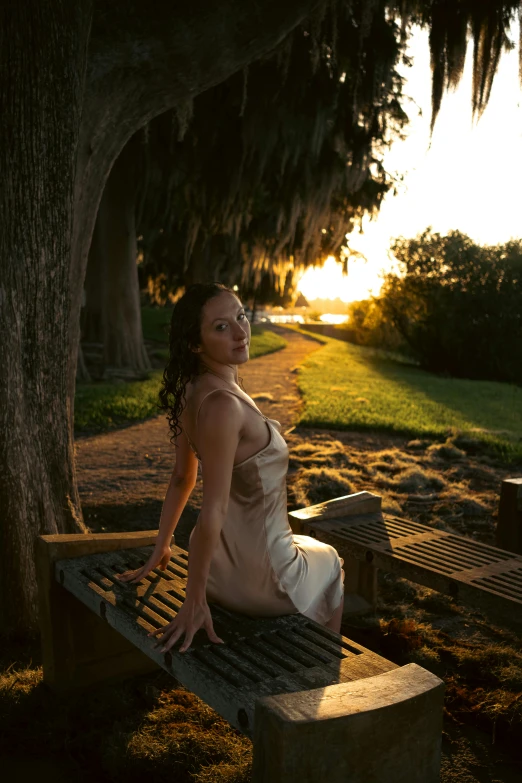 a woman sitting on a bench under a tree