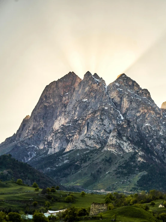 an open field below a majestic mountain range