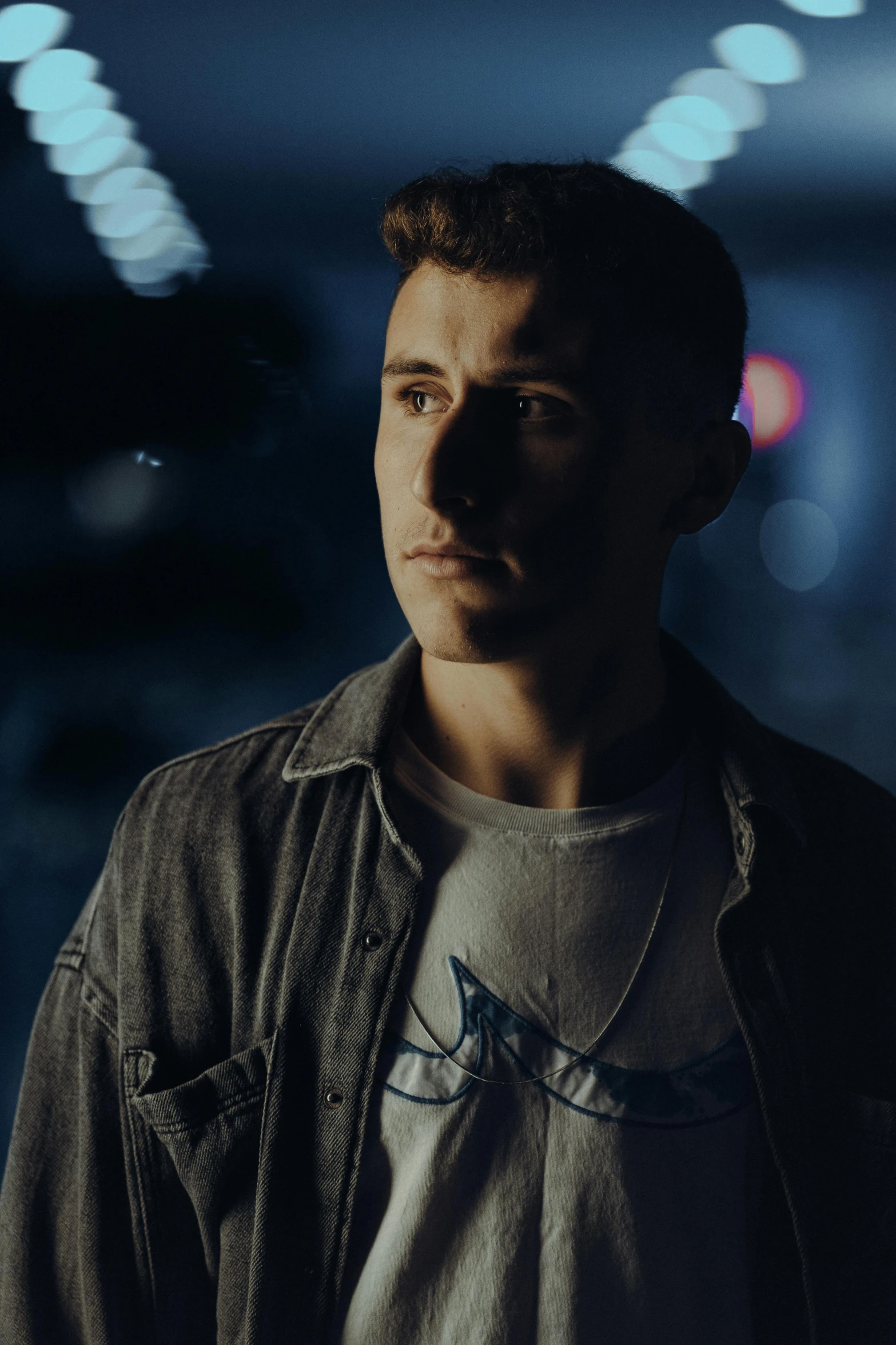 man in black jacket in front of window at night