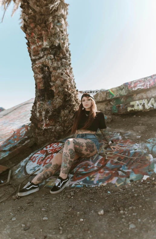 a woman with tattooed legs sitting near a palm tree