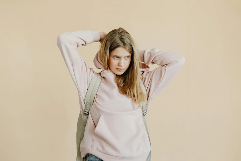 girl with back packs covering her hair, she is wearing a pink sweater