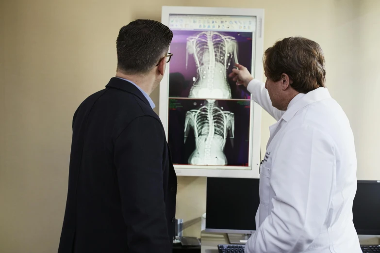 two men pointing at an x - ray in the office