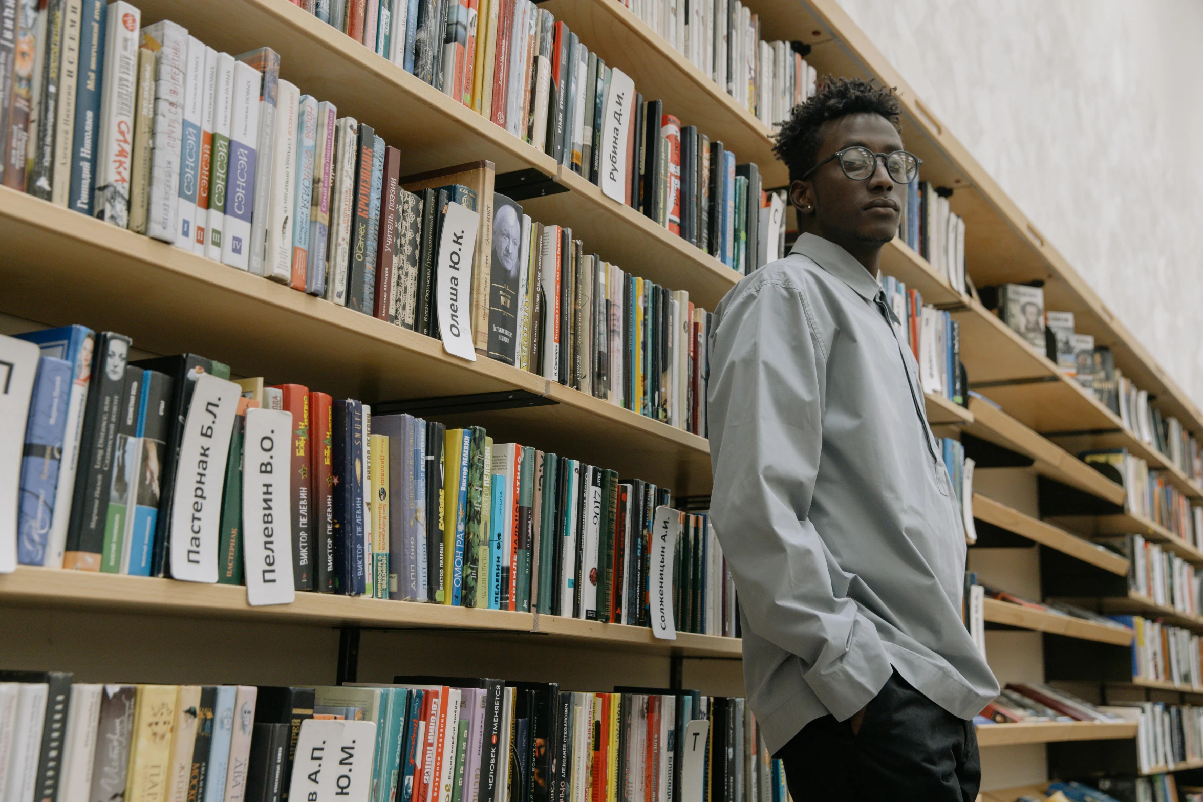 a man leaning against a bookshelf full of books