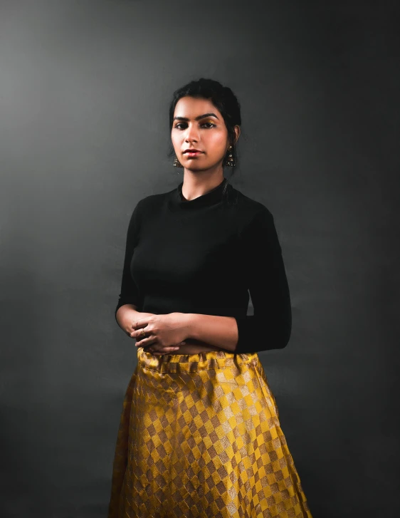 a woman poses for a picture in a black top and yellow skirt