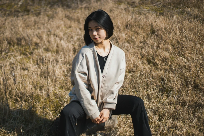 a girl is sitting in a field of tall grass