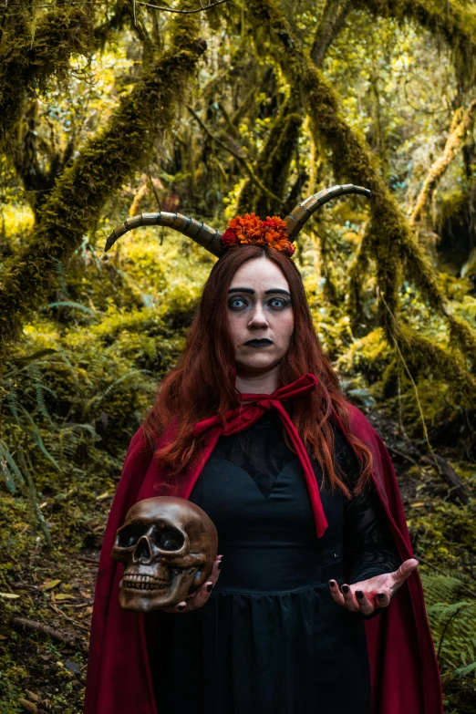 a woman dressed as an evil queen holding up her skull