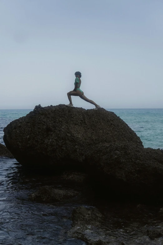 a person sitting on top of a large rock by the ocean