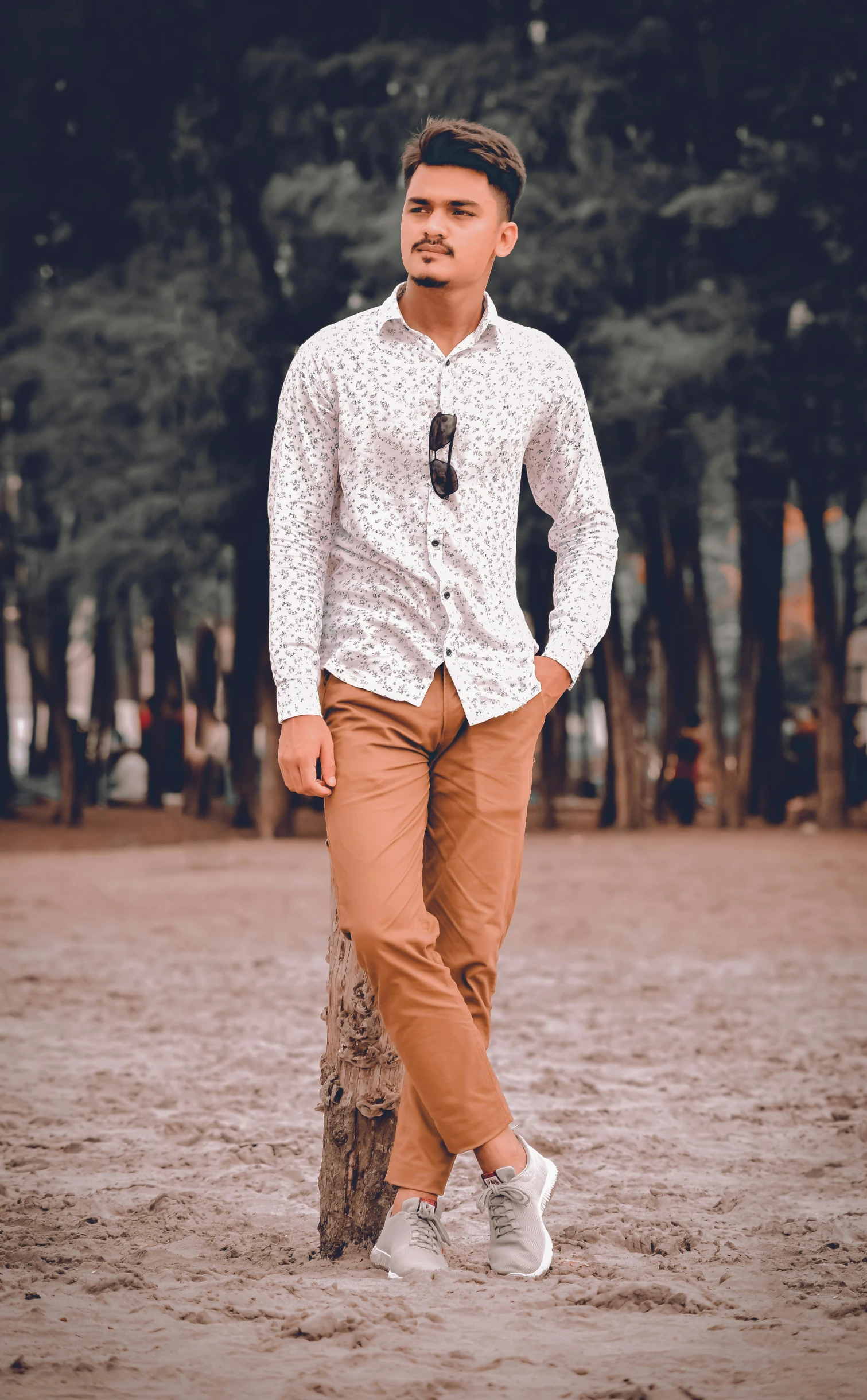 the man poses near a tree trunk in the middle of an outdoor park