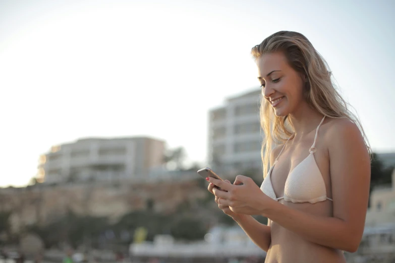 a beautiful woman in a bikini looking at her cellphone