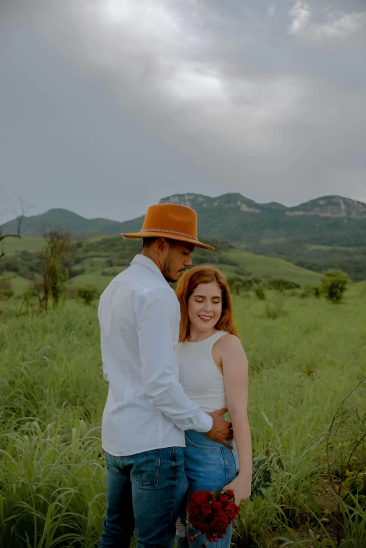 a woman in tight jeans and an orange hat holds her husband