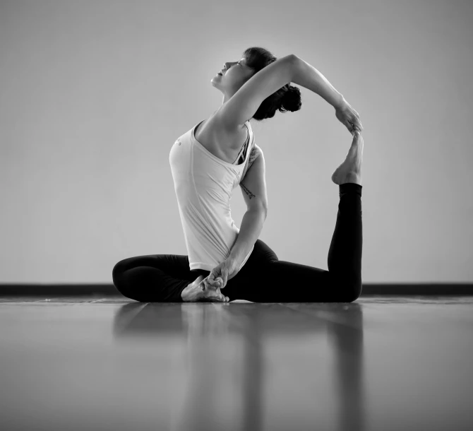 a woman is sitting in a yoga position with one hand on the back and her leg behind her